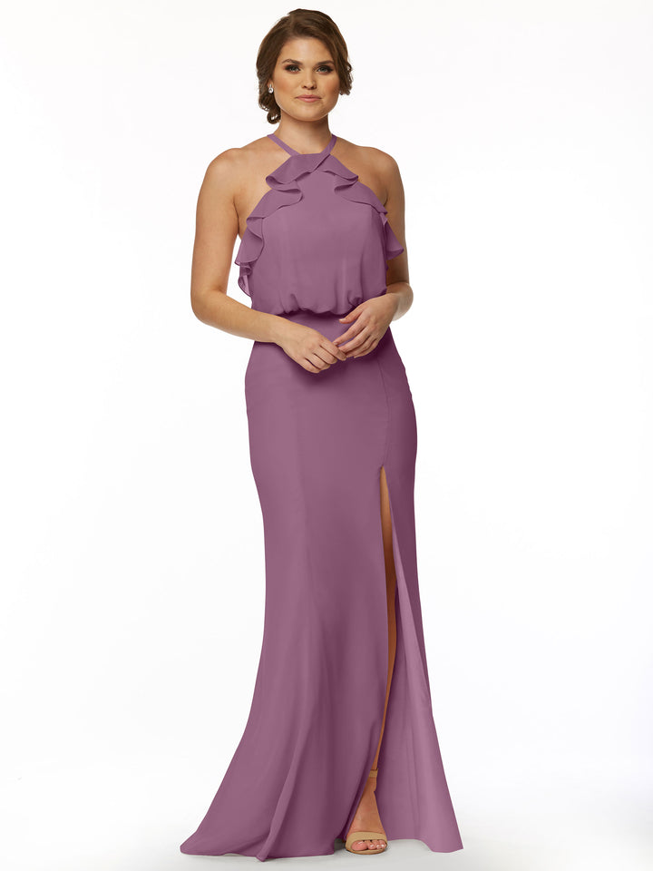 A woman wears Avery Austin’s 80147, a fitted mauve chiffon dress with ruffle bodice details and a front slit, standing against a plain white background.
