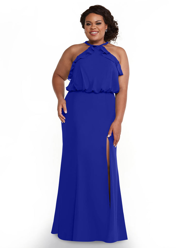 A woman stands smiling against a plain white background, wearing Avery Austin’s fitted chiffon dress (style 80147) featuring a ruffled halter top and a thigh-high side slit.