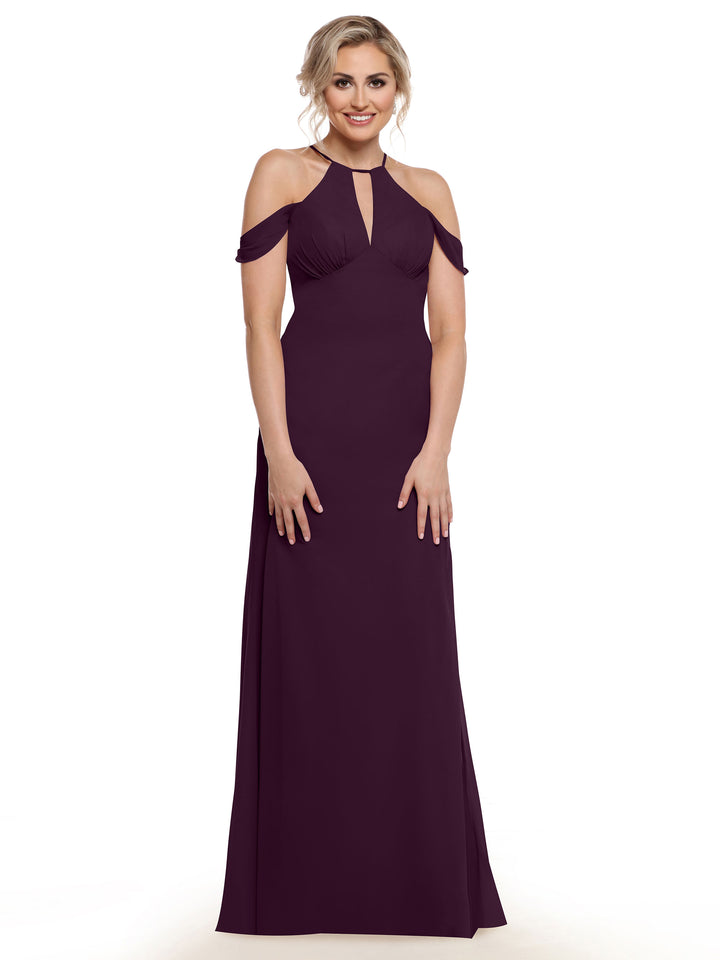 A woman smiles against a plain white background, wearing Avery Austin’s 80148: a floor-length, dark purple off-the-shoulder dress featuring cold shoulder cutouts and a front keyhole detail.