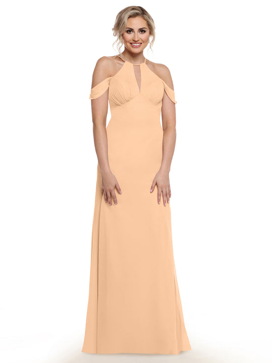 A woman with blonde hair in an updo is smiling and wearing the Avery Austin 80148, a floor-length peach off-the-shoulder dress with a keyhole neckline, standing against a plain white background.