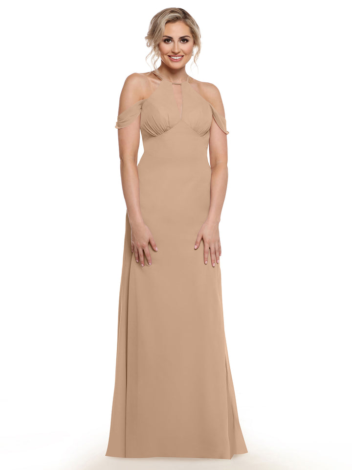A woman in a sleeveless, floor-length beige gown with off-the-shoulder straps from Avery Austin (Style 80148) smiles elegantly against a plain white background, highlighting the off-the-shoulder dress style.
