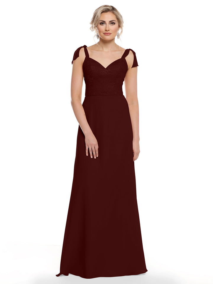 A woman wears Avery Austin style 80149—a long dark burgundy chiffon dress with a floral lace bodice, self-tie shoulder straps, and a sweetheart neckline—against a plain white background.