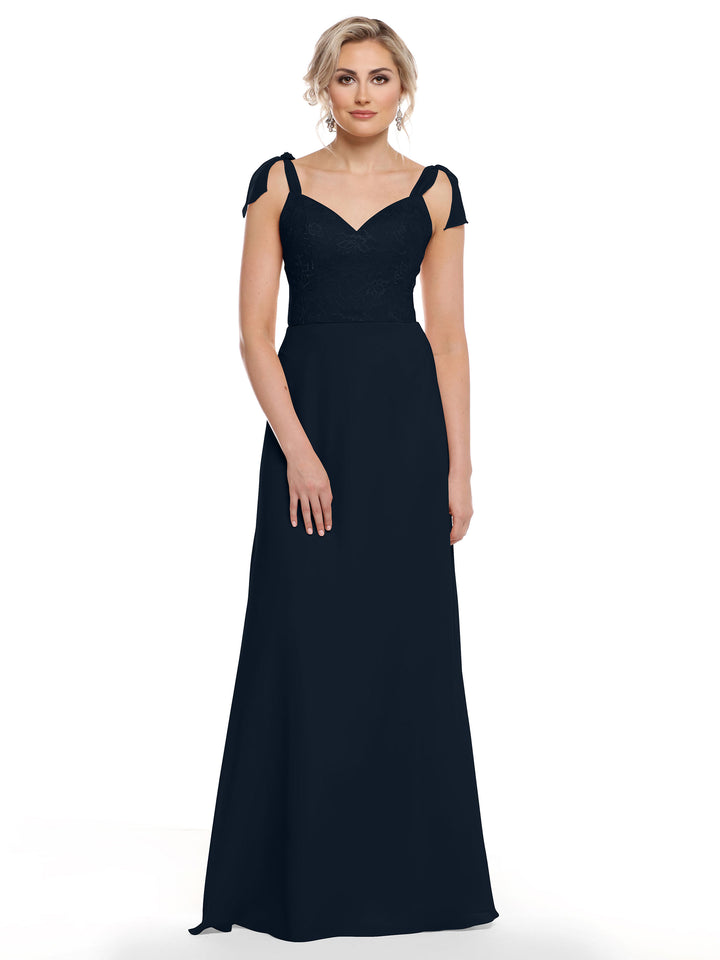 A woman wearing Avery Austin style 80149—a floor-length navy blue chiffon dress with a floral lace bodice, sweetheart neckline, and cap sleeves—stands against a plain white background.