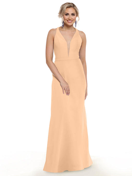A woman wearing Avery Austin’s 80150—a sleeveless, floor-length peach gown with a plunging neckline—smiles against a white background. Her light hair is styled up and she accessorizes with dangling earrings.