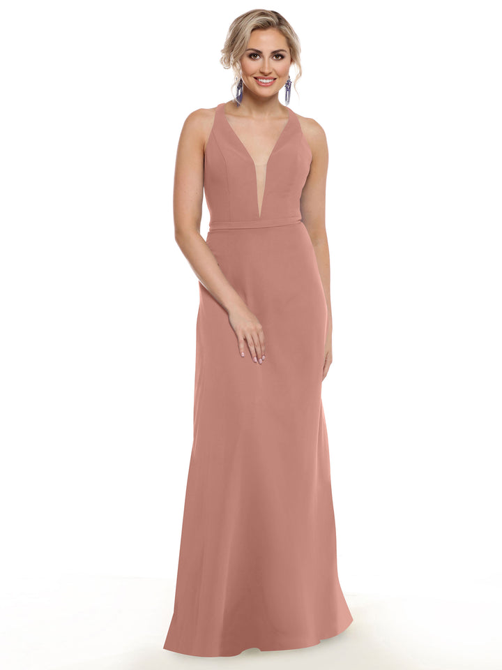 A woman smiles in Avery Austin’s 80150, a sleeveless, floor-length gown with geometric cut-outs and a deep V neckline. She wears her blonde hair up with drop earrings, standing against a plain white background.