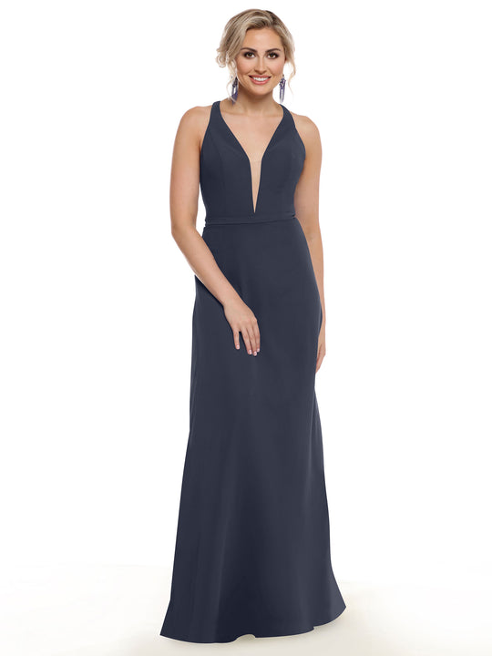 A woman with blonde hair in an updo models Avery Austin’s 80150, a sleeveless, floor-length navy gown with geometric cut-outs and a deep V neckline, smiling against a plain white background.