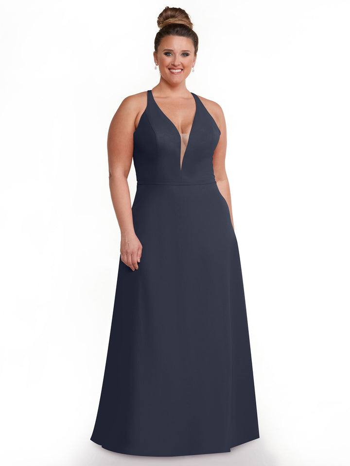 A woman in Avery Austin’s 80150—a sleeveless, floor-length dark blue gown with a deep V-neckline and geometric cut-outs—smiles with her hair in a high bun against a plain white background.