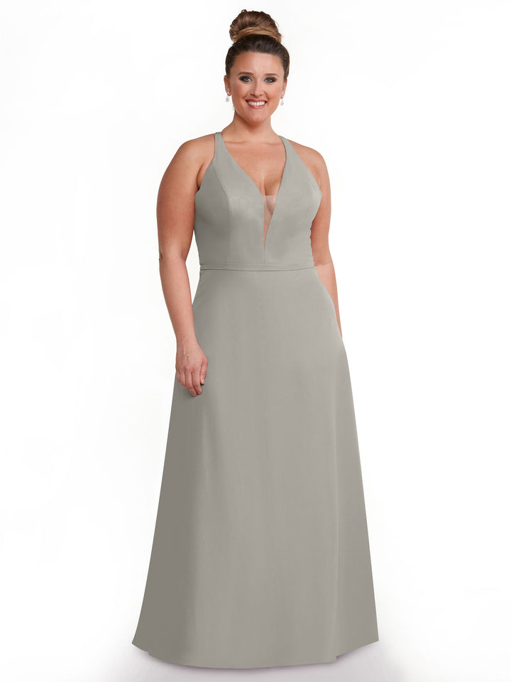 A woman with her hair in a bun wears the Avery Austin TH-80150, a sleeveless, floor-length light gray dress with a plunging neckline and sheer panel, smiling against a plain white background.