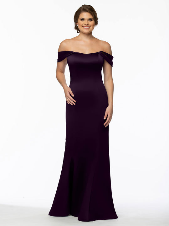 A woman smiles in the Avery Austin 80151 dress—dark purple, off-the-shoulder with convertible straps, a fitted bodice, and a floor-length skirt flowing elegantly against a plain white background.