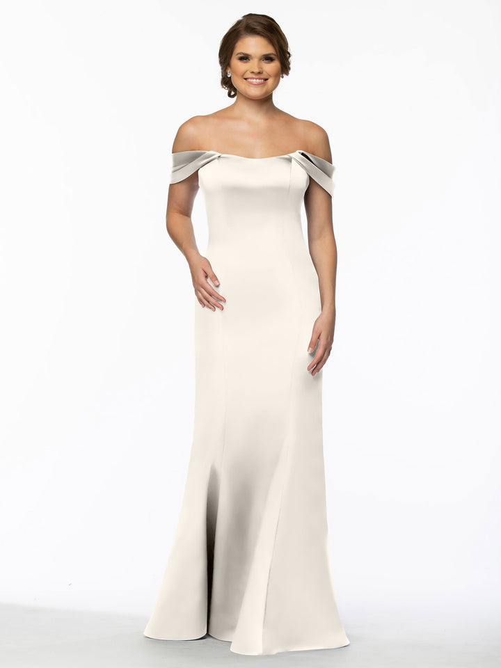 A woman smiles in Avery Austin’s 80151, an off-the-shoulder, floor-length, light gown with a fitted bodice and flared skirt, against a plain white background.