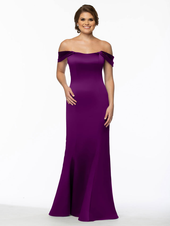 A woman smiles in Avery Austin’s 80151, a floor-length, off-the-shoulder dress with convertible straps and a flared hem, set against a plain white background.
