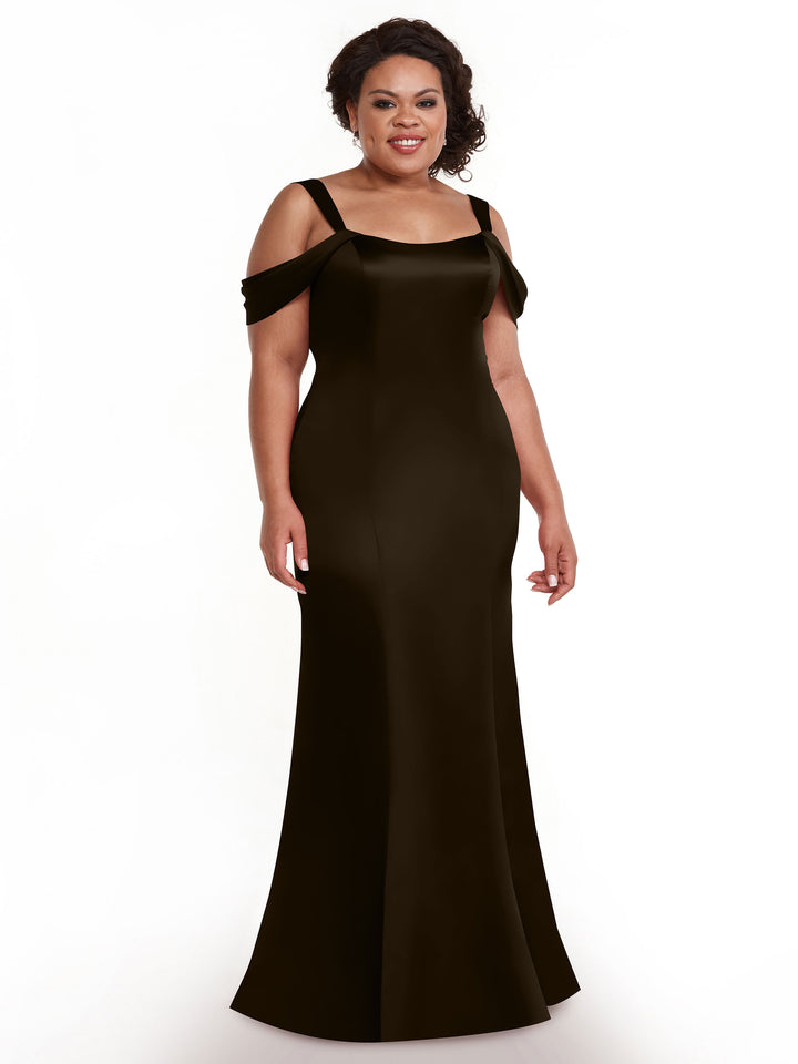 A woman with dark, curly hair styled up smiles against a white background, wearing the Avery Austin TH-80151—a long, chocolate off-the-shoulder dress with a fitted bodice and flared hem.