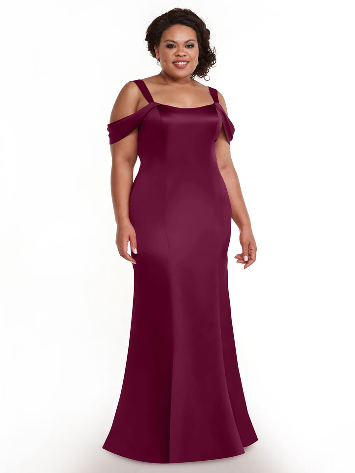 A woman smiles against a plain white background wearing Avery Austin’s 80151, a floor-length, fitted, off-the-shoulder burgundy dress.