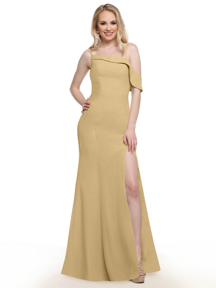 A woman wearing Avery Austin’s 80153: a one-sleeve, light gold chiffon bridesmaid dress with an asymmetrical neckline and high side slit, stands smiling against a white background.