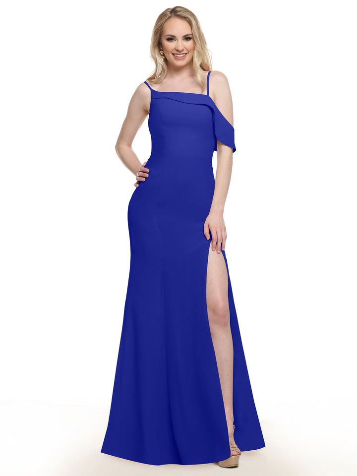A woman in Avery Austin’s 80153 royal blue sleeveless chiffon bridesmaid dress with a thigh-high slit smiles with one hand on her hip. She has light hair, wears nude heels, and stands against a plain white background.