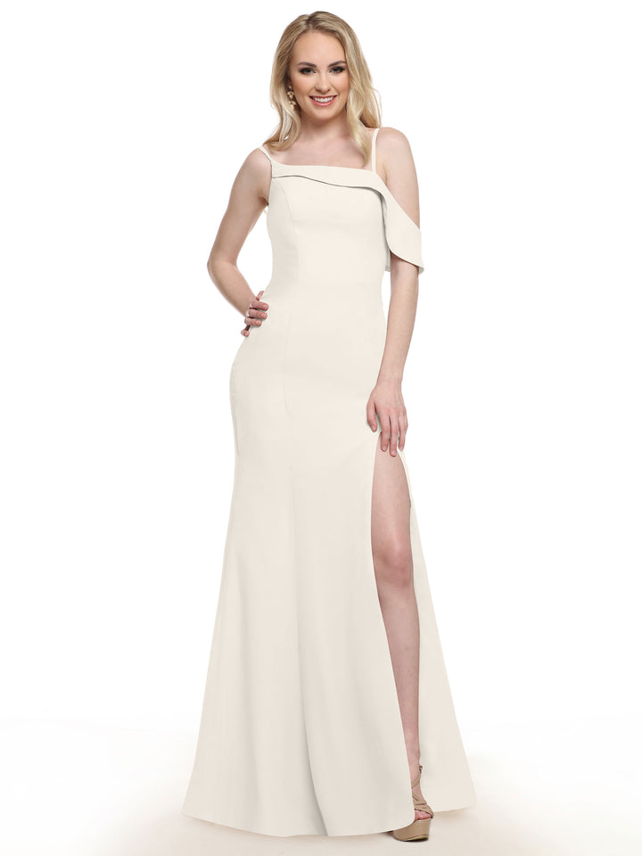 A woman wearing the Avery Austin 80153, a long off-white one-sleeve bridesmaid dress with an asymmetrical neckline and thigh-high slit, smiles with one hand on her hip against a plain white background.