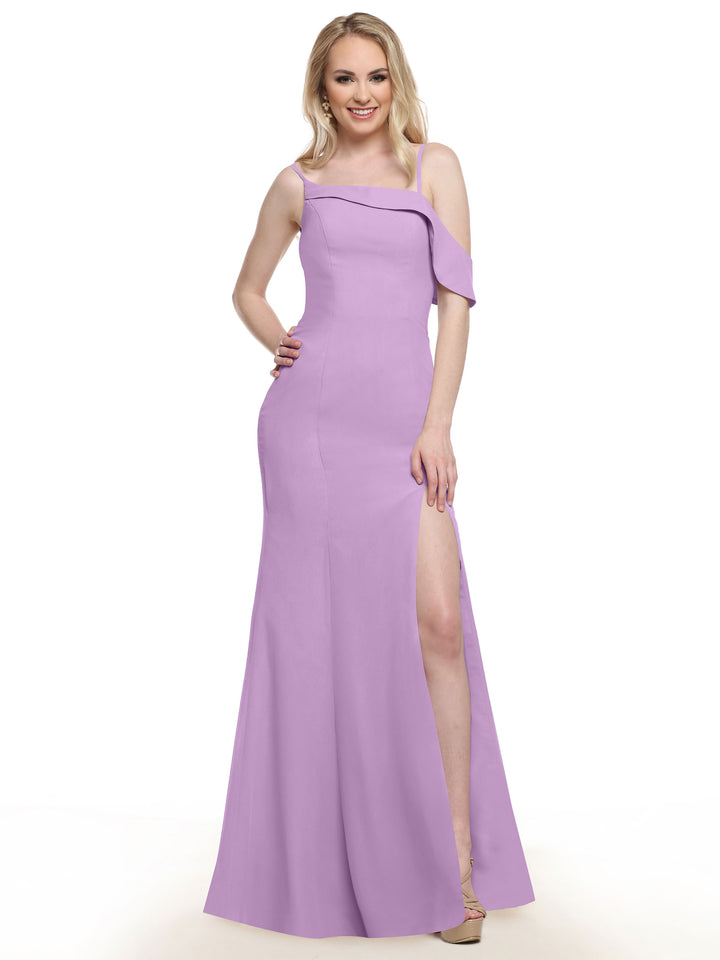A woman in a floor-length Avery Austin 80153 lilac gown with an asymmetrical ruffle sleeve and high slit stands smiling with one hand on her hip against a white background.