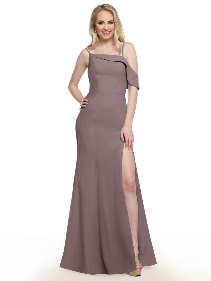 A woman in the Avery Austin 80153 mauve, one-shoulder chiffon bridesmaid dress with a thigh-high slit stands smiling, one hand on her hip and the other by her side. She has long blonde hair and wears nude heels.