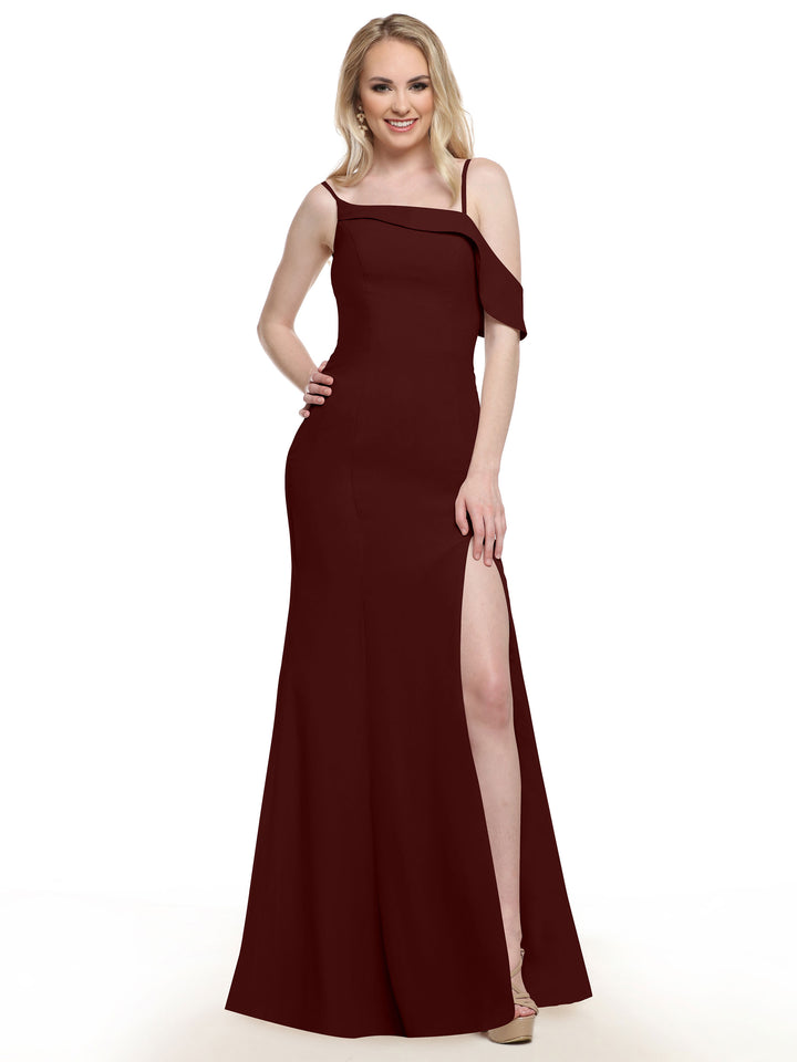 A woman smiles in Avery Austin’s 80153, a sleeveless floor-length burgundy chiffon bridesmaid dress with a side slit. She poses with one hand on her hip, nude heels showing against the white backdrop, her long blonde hair down.