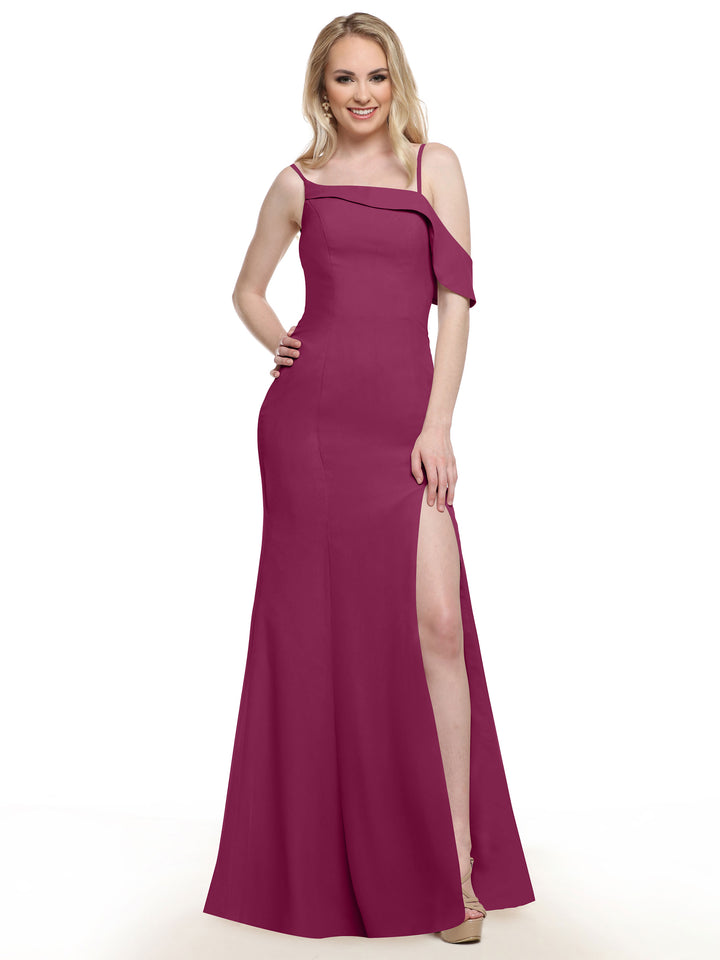 A woman poses confidently in the Avery Austin 80153 magenta chiffon bridesmaid dress, featuring an asymmetrical neckline and high slit. She smiles at the camera, finishing her elegant look with nude heels.