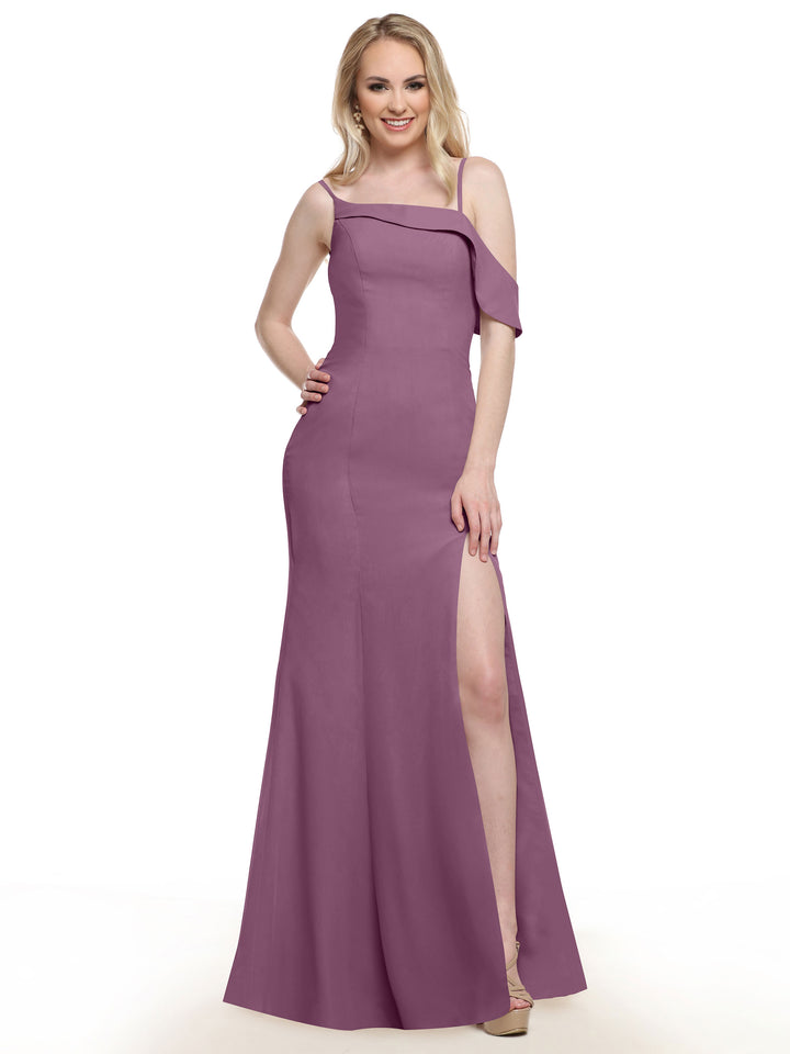 A woman in Avery Austin’s 80153 mauve fit-and-flare bridesmaid dress with an off-shoulder detail and thigh-high slit stands smiling, one hand on her hip, against a plain white background.