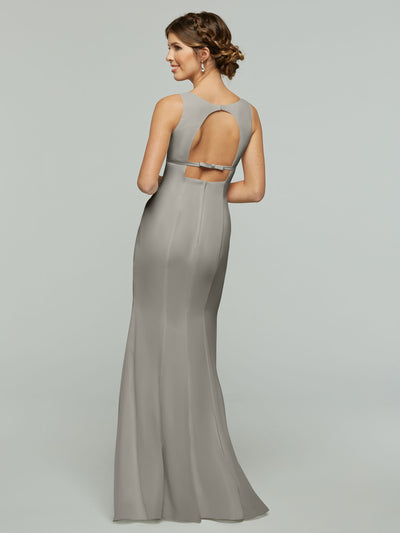 A woman models Avery Austin style 80155, a long silver-gray chiffon fit and flare dress with an open keyhole back, standing and looking over her shoulder against a plain background.