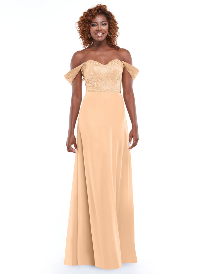A woman wears the Avery Austin 80164 gold off-the-shoulder dress with a lace bodice and chiffon skirt, smiling against a plain white background.