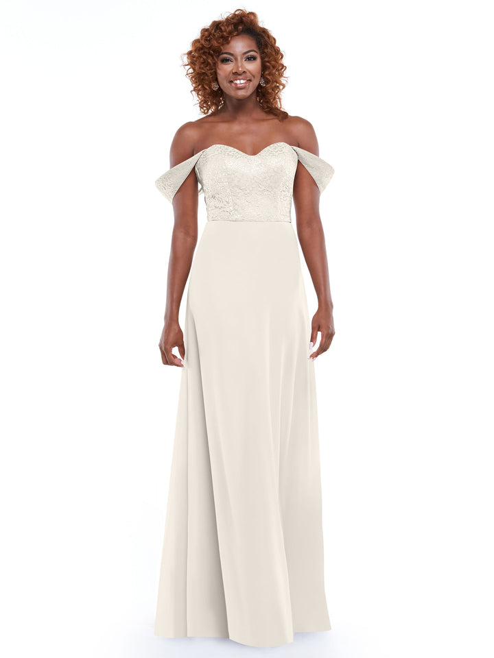 A smiling woman with curly hair models Avery Austin’s 80164, an off-the-shoulder dress with a lace bodice and flowing chiffon skirt, posed against a plain white background.