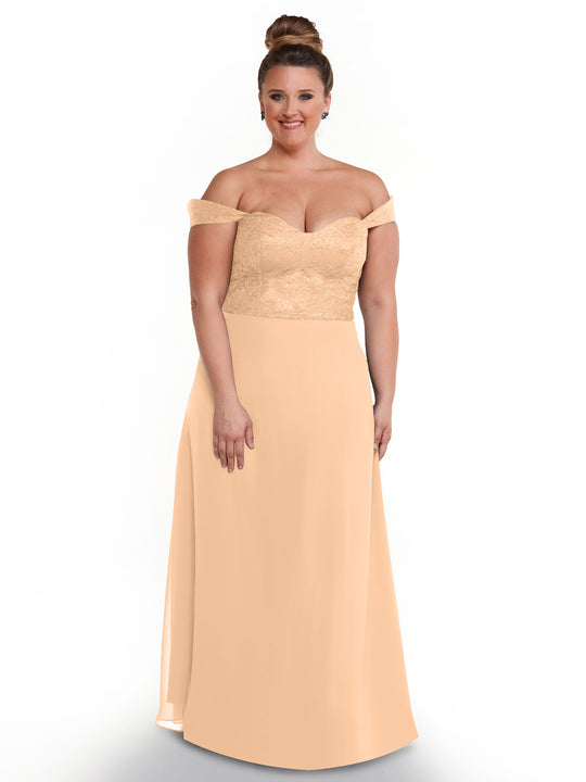 A woman with her hair in a bun models Avery Austin's 80164 off-the-shoulder dress with a lace bodice and flowing chiffon skirt against a plain white background.