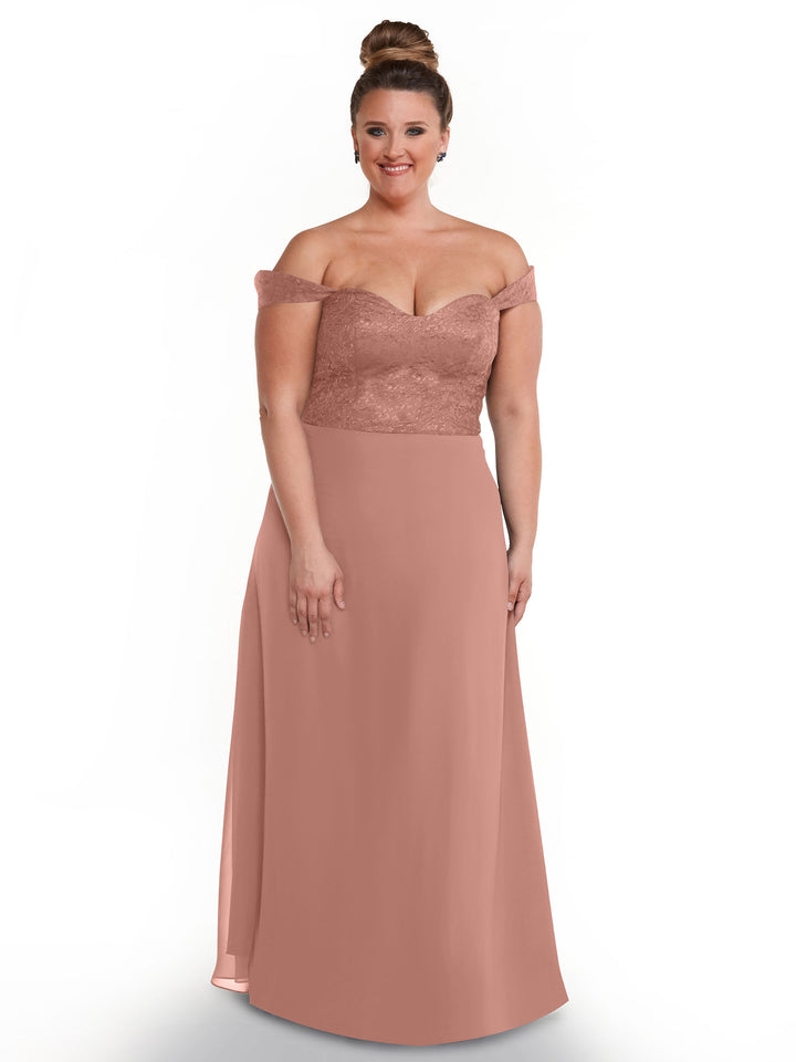 A woman smiles against a plain white background, wearing Avery Austin’s 80164: an off-the-shoulder dress with a lace bodice and flowing chiffon skirt.