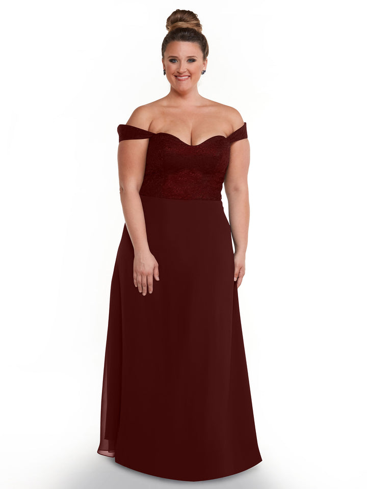 A woman in Avery Austin style 80164, a burgundy off-the-shoulder lace bodice dress with a chiffon skirt, smiles against a white background.
