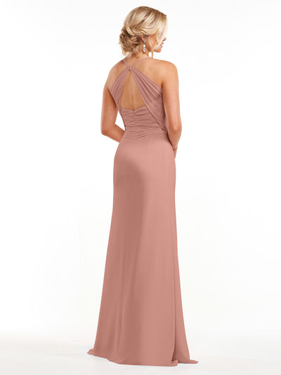 A woman stands with her back to the camera, showcasing the elegant drape and fitted silhouette of Avery Austin’s 80167 blush pink chiffon dress with a ruched bodice and open back, set against a plain white background.