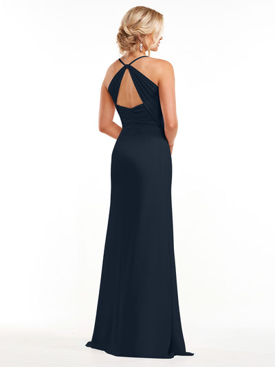A woman models Avery Austin's 80167: a long, elegant navy blue chiffon dress with an open back and crisscross straps. She stands against a plain white background with her hair styled in a neat updo, facing away from the camera.