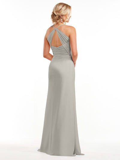 A woman, her blonde hair in a low updo, models Avery Austin’s 80167: a long chiffon dress with a ruched bodice and sweetheart neckline. She stands facing away against a plain white background, wearing dangling earrings.