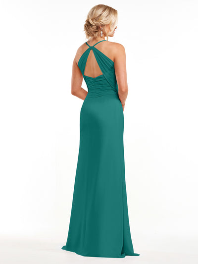 A woman wears Avery Austin’s 80167, a long teal chiffon dress with ruched detailing, open back, and delicate spaghetti straps. She stands facing away, her blonde updo and dangling earrings highlighted against a white background.