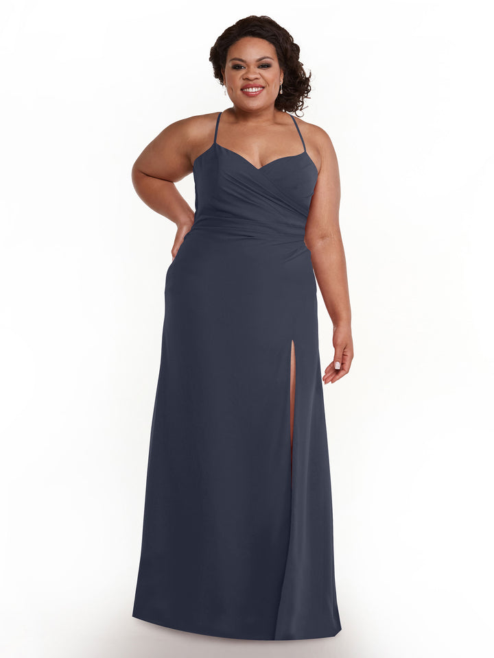 A woman wearing Avery Austin’s 80167 dress in indigo—chiffon with spaghetti straps, sweetheart neckline, and a thigh-high slit—stands smiling against a plain white background.