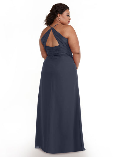 A woman with short, curly hair and earrings faces away in Avery Austin’s 80167 gown—a sleeveless, floor-length dark blue chiffon dress featuring a ruched bodice, keyhole back cutout, and crisscross straps. The background is white.