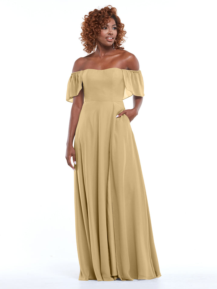 A woman stands against a white background wearing Avery Austin’s 80168—an off-the-shoulder, champagne chiffon A-line dress with ruffled sleeves and side pockets, combining elegance and practicality.