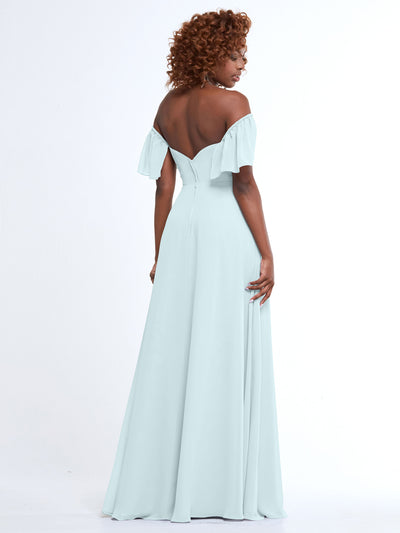 A woman with curly hair models Avery Austin’s style 80168, a light blue chiffon off-the-shoulder A-line dress, standing with her back to the camera against a plain white background.