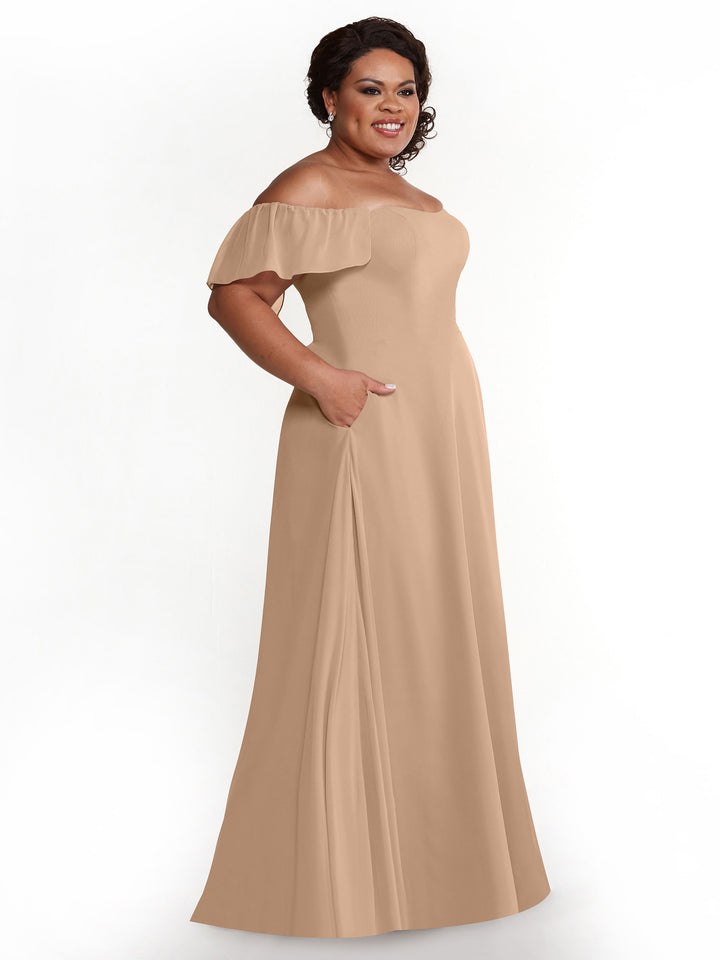 A woman models the Avery Austin 80168, a buff chiffon off-the-shoulder A-line dress with pockets and short ruffled sleeves, posing against a plain white background.