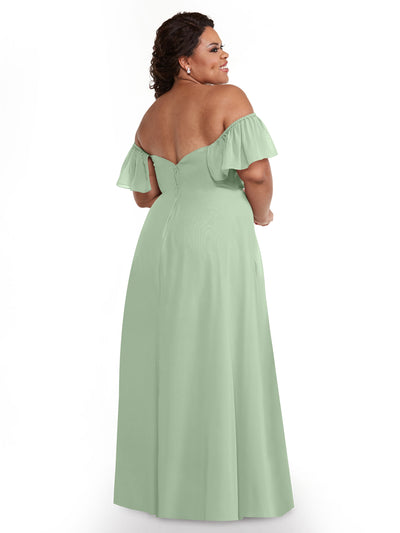 A woman wearing Avery Austin's 80168, a light green chiffon off-the-shoulder A-line gown with ruffled sleeves and fitted bodice, stands with her back to the camera, looking over her shoulder and smiling.