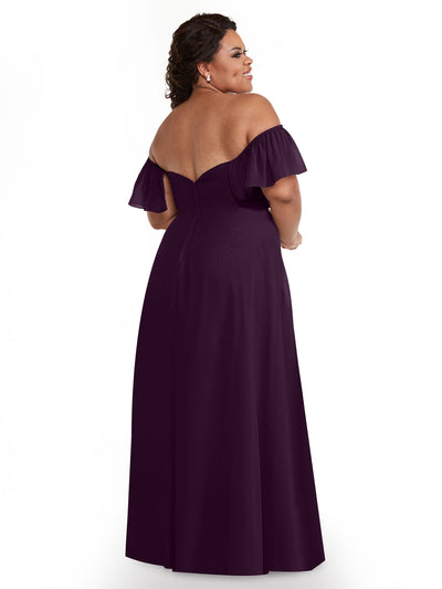A woman with curly brown hair, smiling, stands facing away to show the pockets on the Avery Austin 80168 chiffon off-the-shoulder, floor-length A-Line dress.