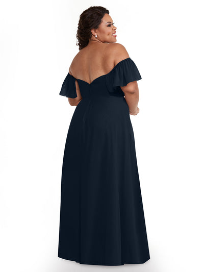 A woman stands facing away, showcasing the elegant back of Avery Austin's 80168—a navy chiffon off-the-shoulder A-line dress with pockets. She wears earrings, has curly hair, and is set against a plain white background.