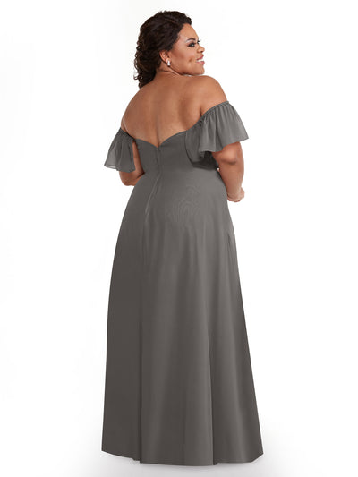 A woman stands facing away, showcasing the back of Avery Austin’s 80168—a long, chiffon off-the-shoulder A-Line dress with ruffled sleeves—against a plain white background.