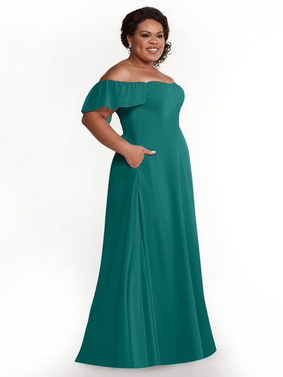 A woman smiles in Avery Austin's 80168: a teal chiffon off-the-shoulder A-line dress with short ruffled sleeves and pockets, posed against a white background.