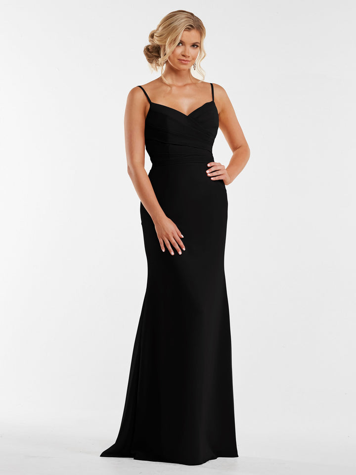 A woman poses against a white background wearing the Avery Austin 80169, a long black evening gown with a pleated bodice and thin straps. Her hair is in soft waves, and she rests one hand on her hip.