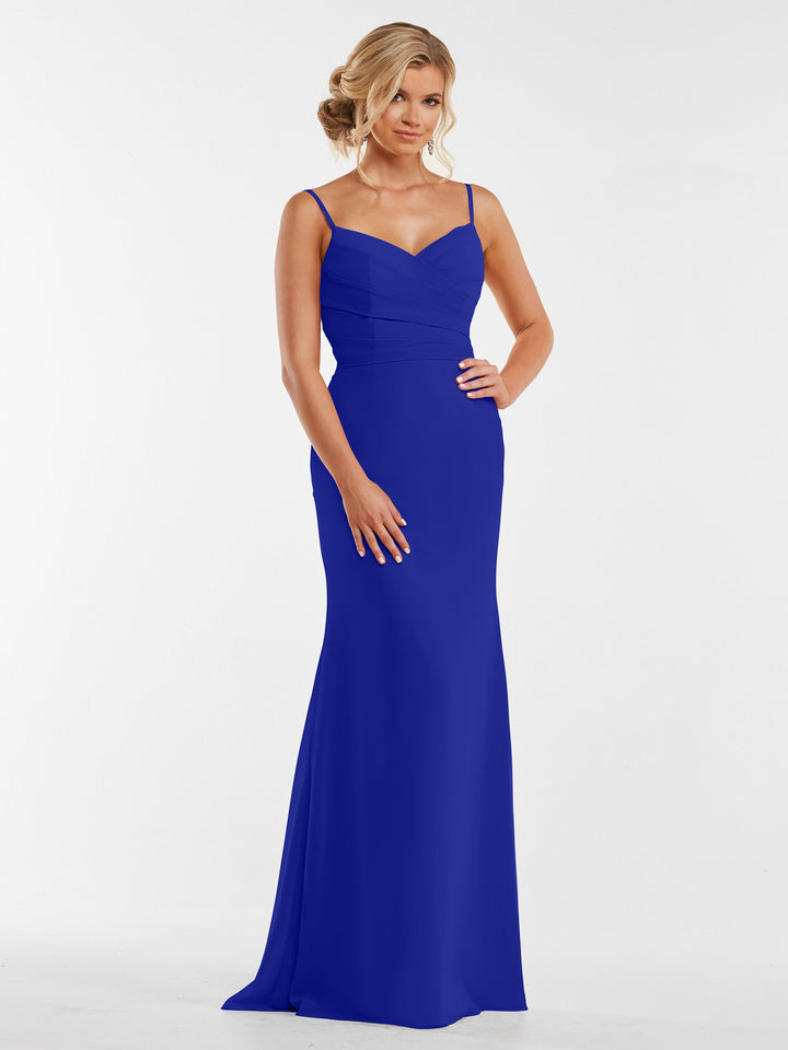A woman with blond hair in an elegant updo wears Avery Austin style 80169, a cobalt floor-length chiffon dress with pleated bodice and spaghetti straps, standing against a plain white background.