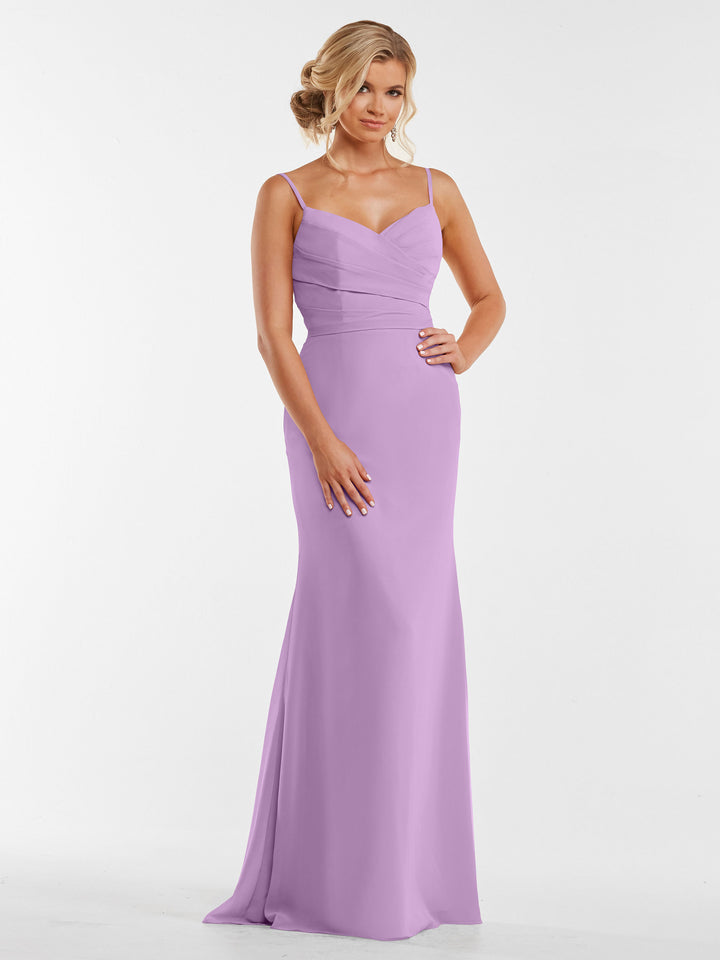 A woman with blonde hair in an elegant updo, hands gently clasped, models Avery Austin style 80169—a long light purple chiffon dress with a pleated bodice—against a plain white background.