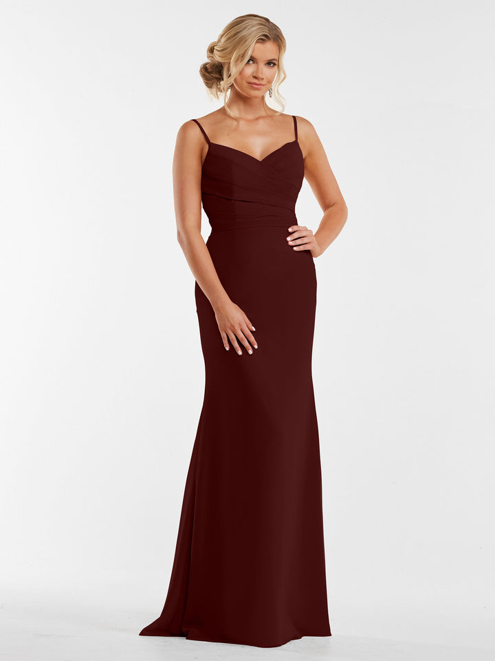 A woman in the Avery Austin 80169 floor-length merlot chiffon dress with thin straps and a pleated bodice stands against a plain white background.
