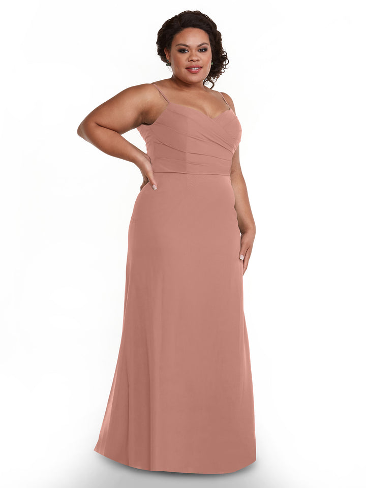 A woman poses against a plain white background wearing Avery Austin style 80169, a sleeveless blush pink chiffon dress featuring a pleated bodice and sweetheart neckline.